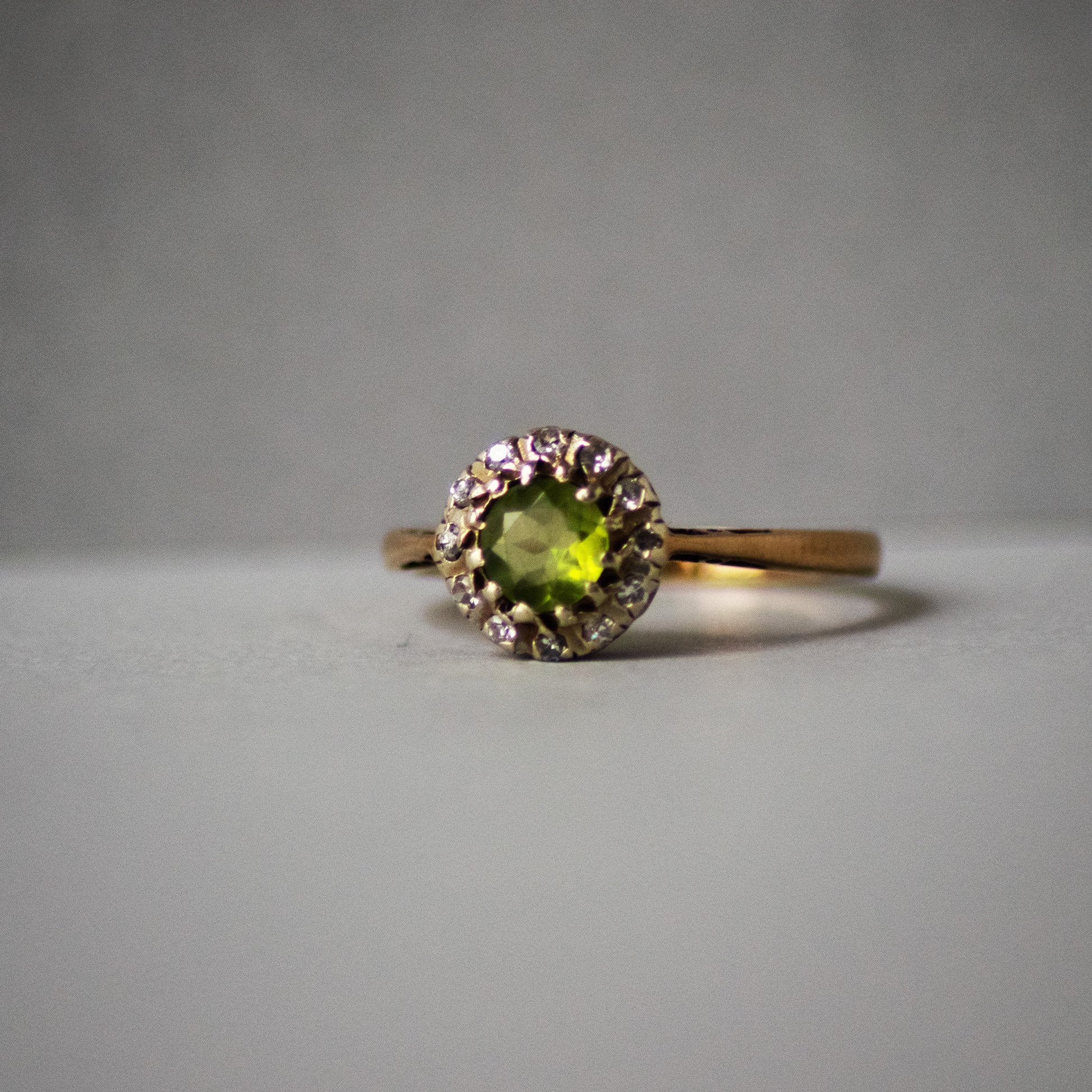 Gold ring with a green gemstone on a gray background
