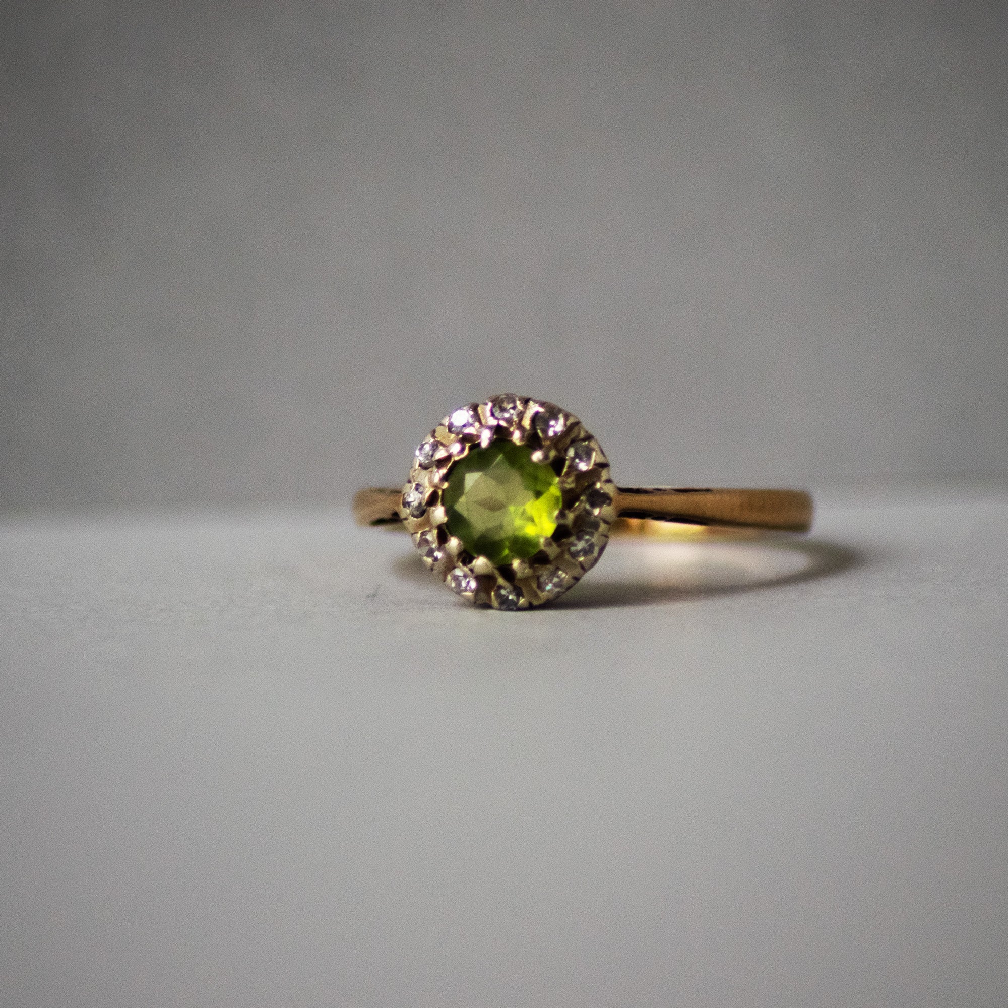 Gold ring with a green gemstone on a gray background