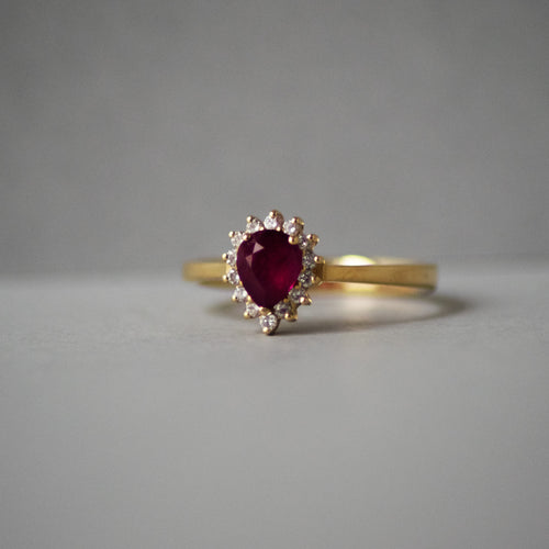 Gold ring with a red gemstone on a gray background