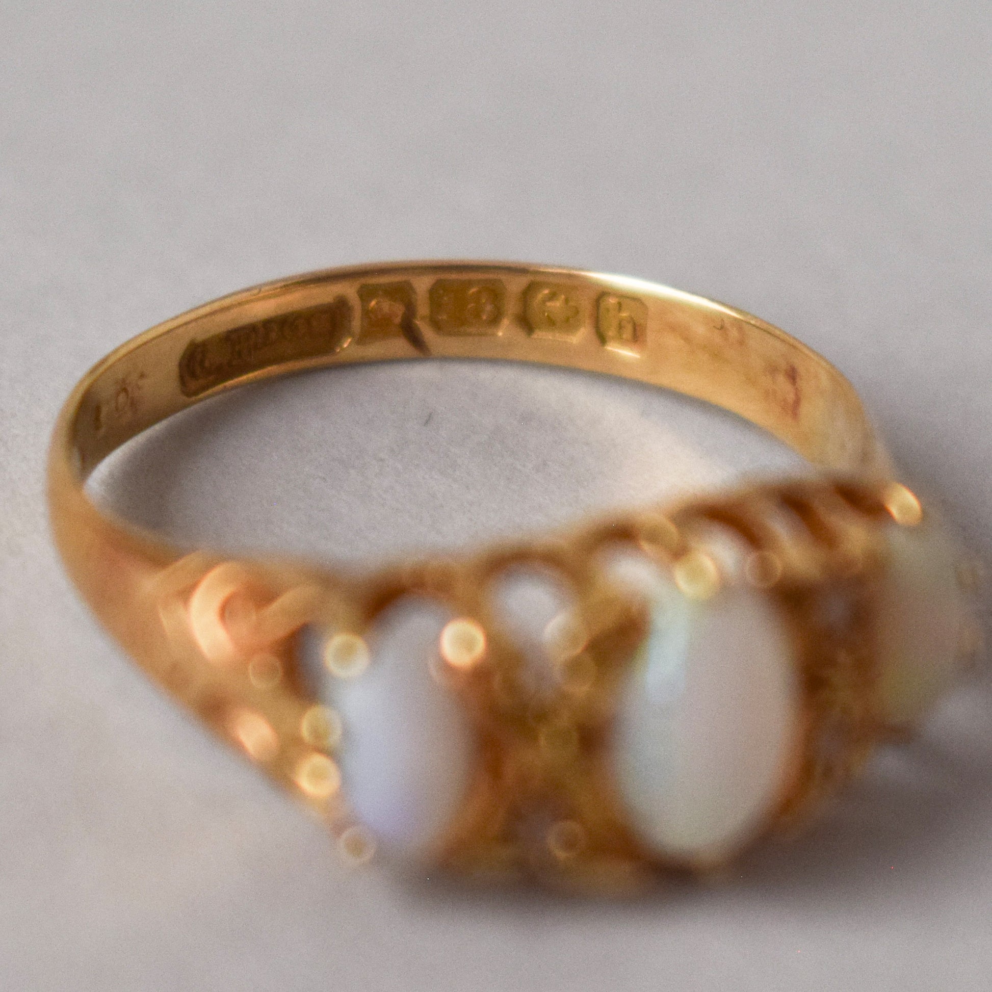 Gold ring with opal stones on a light gray background