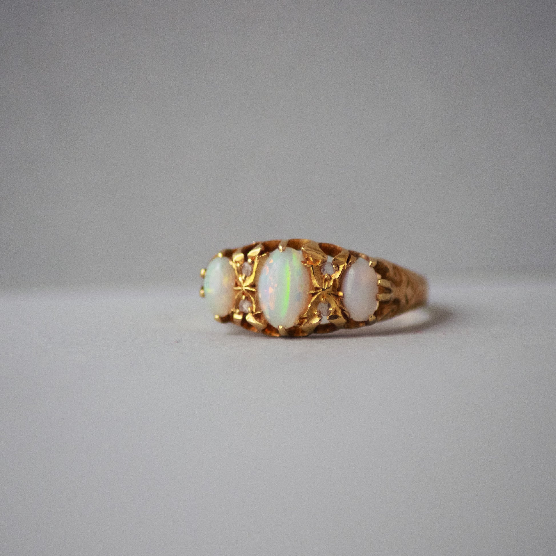 Gold ring with opal stones on a gray background